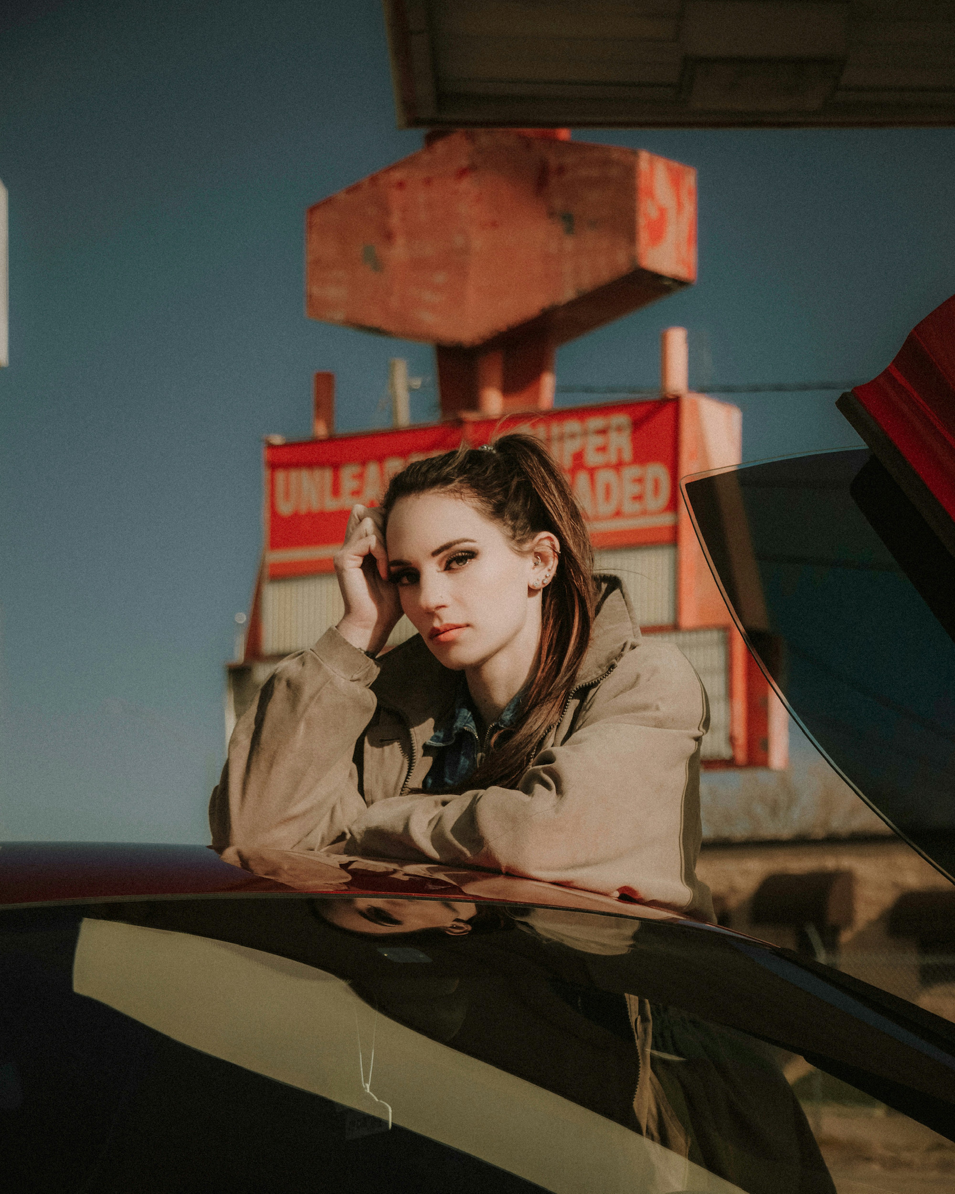 woman in brown coat standing beside red building during daytime